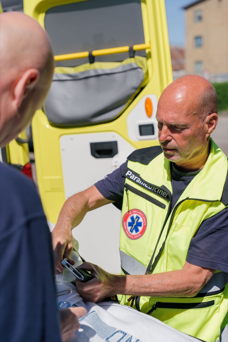 Paramediciner fra DK Ambulancetjeneste tilser en patient ved ambulancen